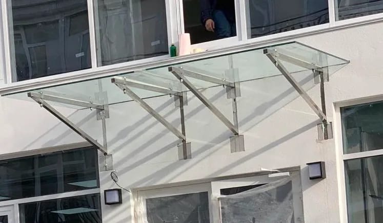 Стеклянный козырёк из триплекса над входом на кронштейнах из нержавеющей стали